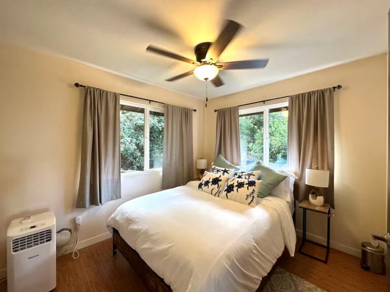 Bedroom with a white bed, corner windows and ceiling fan at H5 Blue Lagoon of Kona Estate