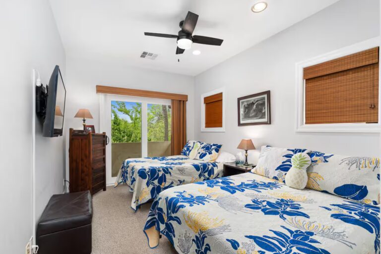 Bedroom with two beds and blue floral bedding at Kona Luxury Estate