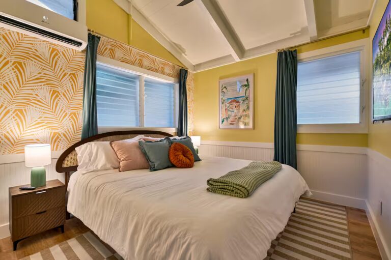 Yellow bedroom with a curved headboard and corner windows at Spacious Kona Retreat