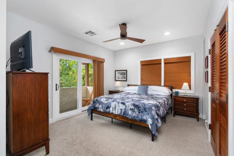 Bedroom with tropical bedding, television and patio doors at Kona Luxury Estate