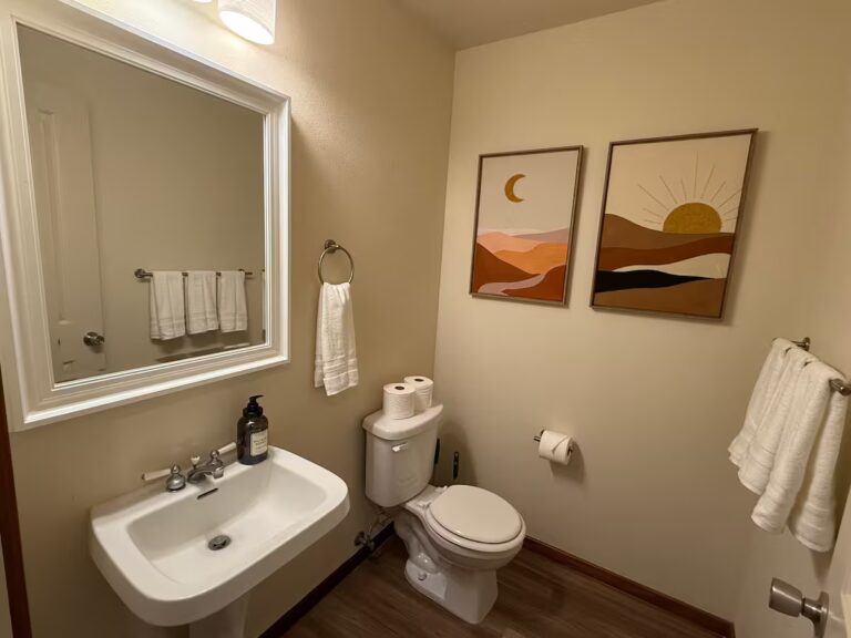 Bathroom with a wall-mounted sink and landscape artwork at HI8 Kona vacation home