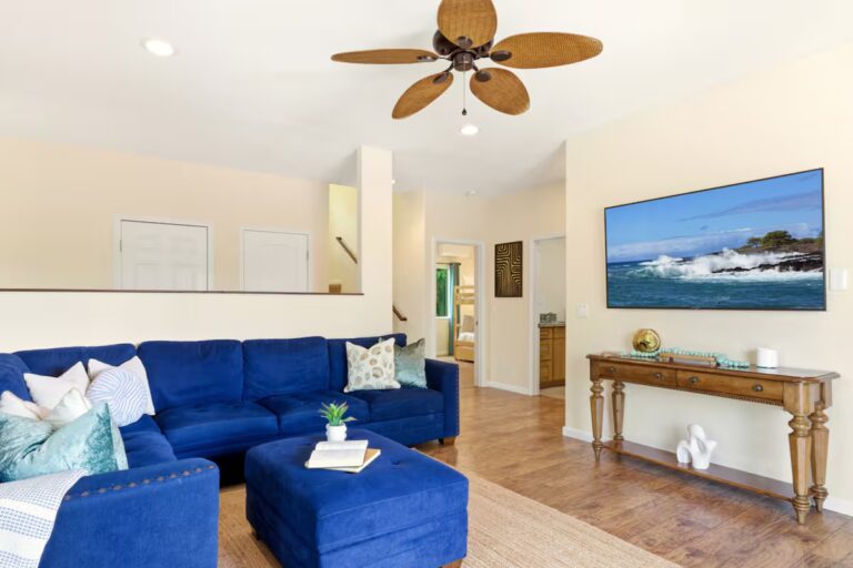 Blue living room seating facing a wall-mounted television at H12 Kona home