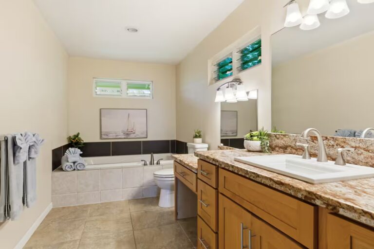 Bathroom with twin sinks and a corner bathtub at H12 Kona home