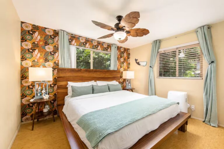 Bedroom with a wood headboard and floral accent wall at Kona Retreat with Hot Tub, Tiki Bar and Pickleball