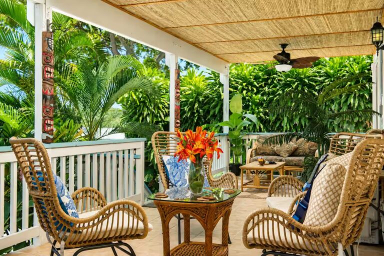 Wicker chairs on a shaded lanai surrounded by tropical plants at Kona Retreat with Hot Tub, Tiki Bar and Pickleball