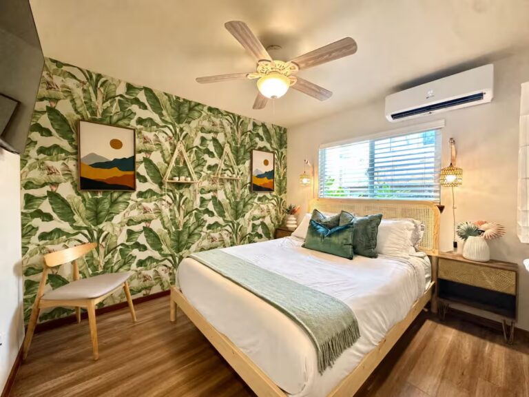 Bedroom with botanical wallpaper and corner windows at HI8 Kona vacation home