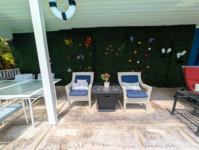 Poolside seating beside a green decorative wall at H7 Kona home