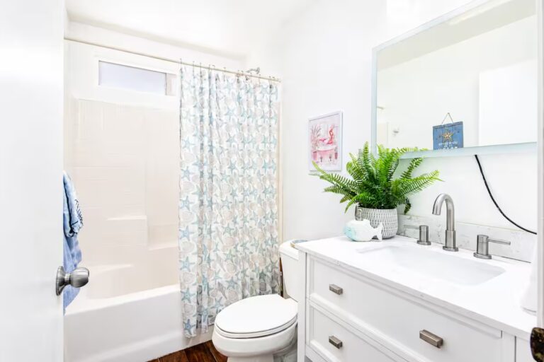 White bathroom vanity beside a patterned shower curtain at Kona Retreat with Hot Tub, Tiki Bar and Pickleball