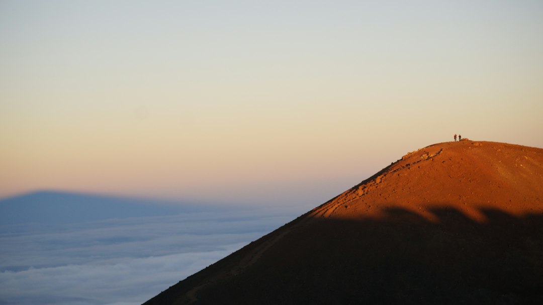 Maunakea mountain shadow across clouds at sunset