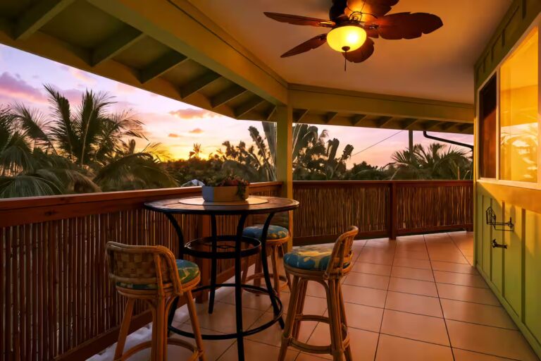 Covered balcony with a small dining table at sunset at H12 Kona home