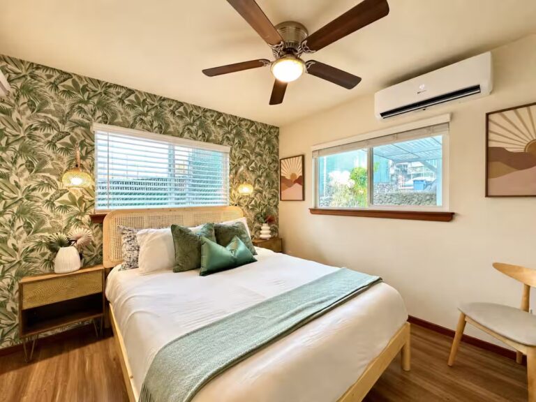 Bedroom with a green botanical accent wall and wood bedframe at HI8 Kona vacation home