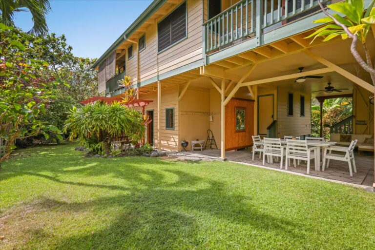House exterior with an upper balcony and lawn-side dining area at H6 Dolphin Bay Estate