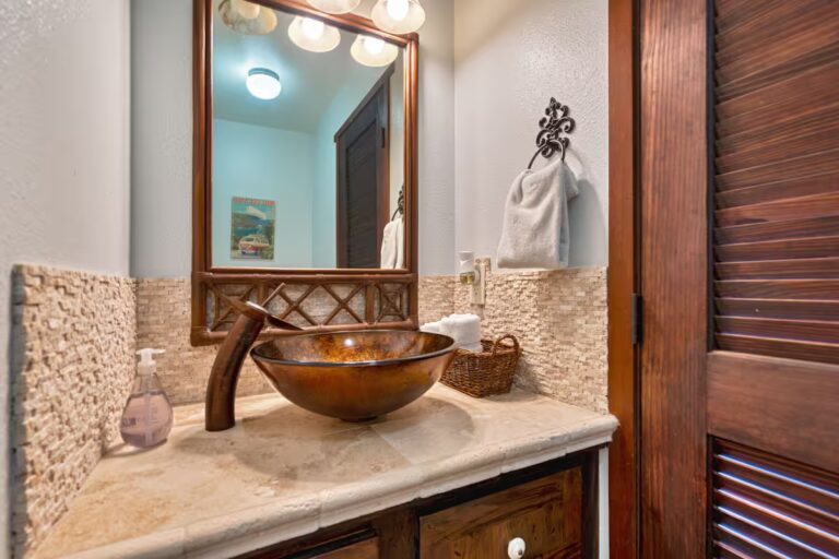 Bathroom with a copper-colored vessel sink and wood trim at H4 Kona home