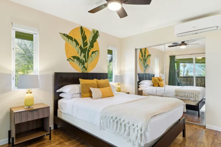 Bedroom with yellow cushions and a painted leaf accent at H12 Kona home