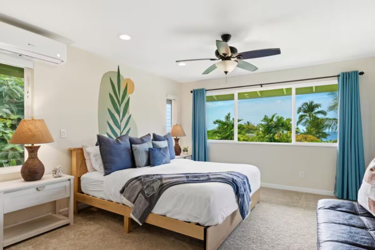 Bedroom with blue curtains and a large painted leaf at H12 Kona home